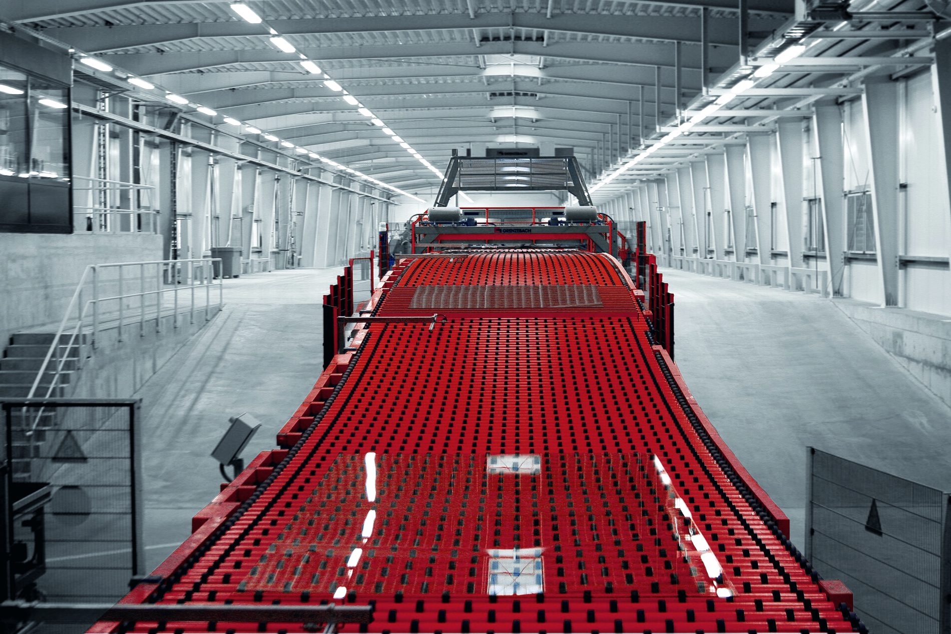 Galpão industrial de grande porte, com linha transportadora atravessando toda a extensão