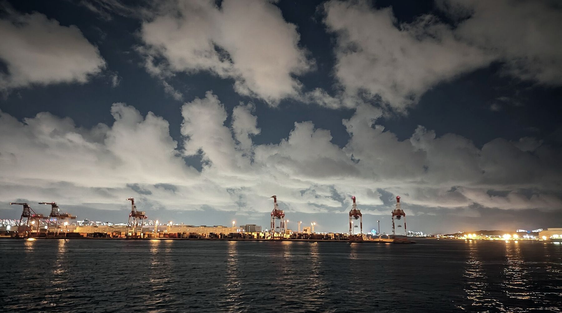 Port yard at dusk, with container cranes silhouetted against the sky